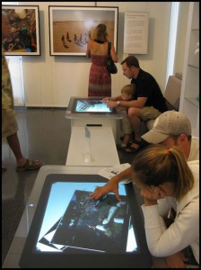 A young family has fun exploring the capabilities of the Microsoft surface table, where you can move, rotate, sort through, and enlarge digital images with the touch of your fingertips. Courtesy © Susan Katz, 2010