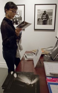 A Woman looks over printed materials at Ken Light's opening at Umbrage Books. Courtesy, ©Suzie Katz 2012