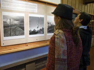 Visitors enjoy looking at Ken Light's photographs "Sign With Bullets," "Rope Swing," and "Tule Fog" during his opening reception in Berkeley, California. Courtesy, ©Suzie Katz 2012
